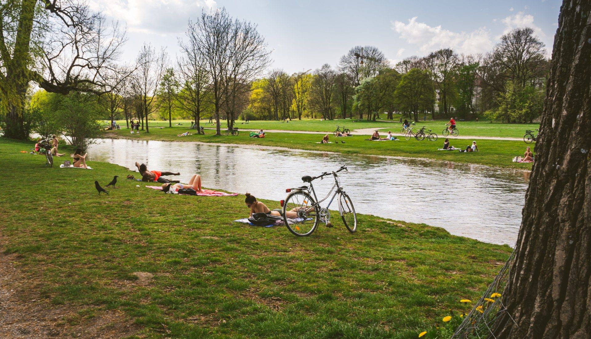 People relaxing on the grass by the water in the English Garden in Munich